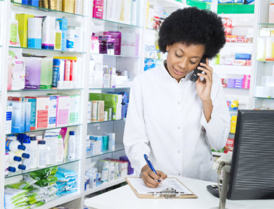 Young female chemist writing on clipboard