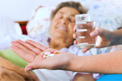 Elderly woman taking pills with glass of water